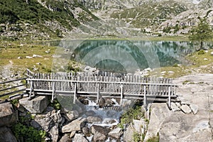 frontal aerial view of wooden bridge over cornisello lake with fir tree photo