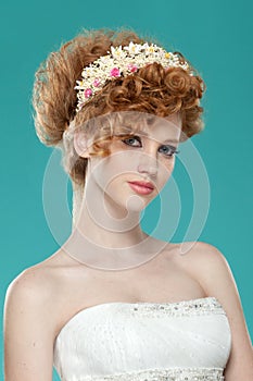 Frontal beauty portrait of a red hairred girl with hairdressed and speckle, with naked shoulders, over blue background