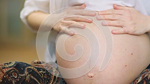 Frontal closeup young pretty pregnant women in retro vintage skirt cowering on big gymnastic ball