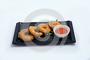 Frontal Hero shot of an appetizer platter of onion rings with lettuce and tomato chutney on a minimal white background with