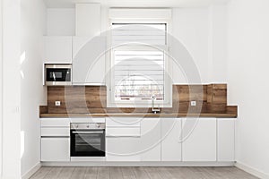 Frontal image of a newly installed modern kitchen with backsplash and countertop of the same material