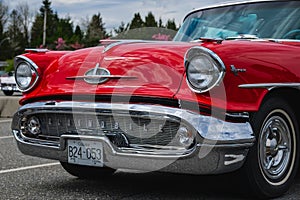 Frontal photo of a classic luxury red car. Color detail on the headlight of a vintage car. Front of an old American car