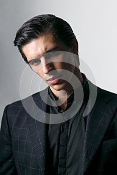 Frontal portrait of a business man dressed in black suit against a dark background