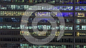 Frontal view of night facade of building with a lot of windows with light timelapse.