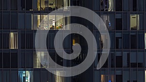 Frontal view of night facade of building with a lot of windows with light timelapse.