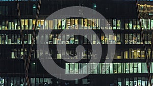 Frontal view of night facade of building with a lot of windows with light timelapse.