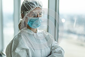 Frontliner doctor in a depressed sad mood in white blue stripe jumpsuit wearing transparent protective shield handling Covid-19