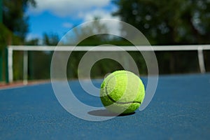 Frontview of bright tennis ball on blue carpet of opened court.