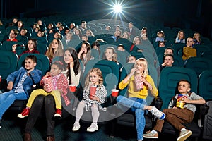 Frontview of emotional adults and children watching film in the new cinema.