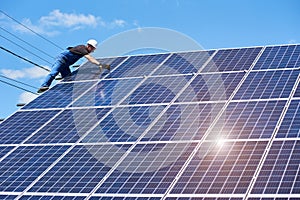 Frontview of man mounting modern solar batteries on house`s roof.