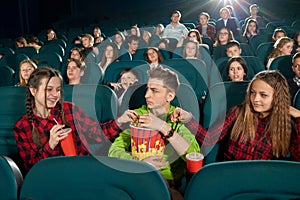 Frontview of three friends eating popcorn by watching movie.