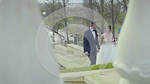 Frontview of a wedding couple walking up to stairs and holding hands