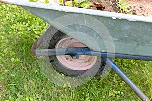 Frontwheel of wheelbarrow standing on the lawn of a garden, gardening and horticulture concept