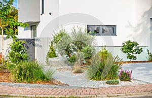 The frontyard of a modern house, garden details with colorful plants and dry grass beds with path