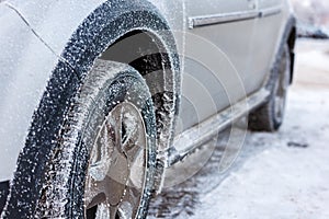 frost covered car wheel at cold winter morning