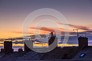 Frost covered roofs and chimneys and sunrise