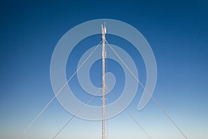 Frost covered telecommunications mast against blue sky