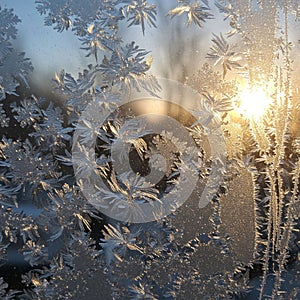 Frost patterns adorn a window, creating intricate designs resembling snowflakes and