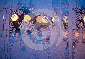 Frost patterns intricately form on a window, highlighted by a