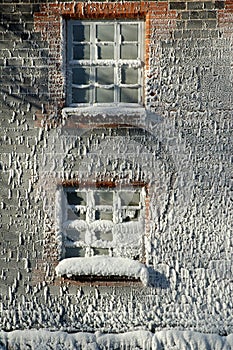 Frost and rime ice covered windows and brick wall