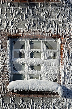 Frost and rime ice covered windows and brick wall