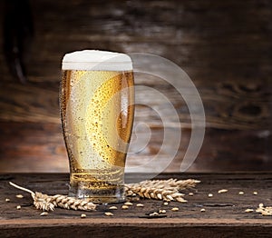 Frosted glass of beer on the wooden table.