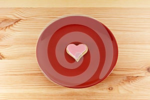 Frosted heart-shaped cookie on a red plate