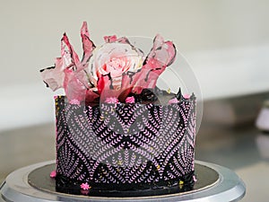 frosted icing black decorate cake for birthday celebration, real rose topping and pink sweet swirls