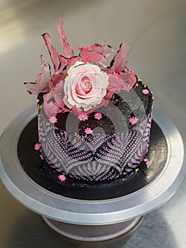 frosted icing black decorate cake for birthday celebration, real rose topping and pink sweet swirls