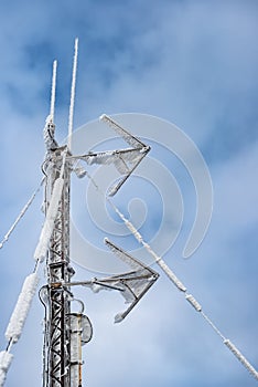 A frosted rusty metal pole with arrow-shaped antennas