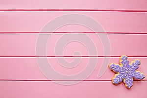 Frosted snowflake cookie on pink wooden table, Christmas dessert, copy space