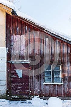 Frosted wooden wall, door and window on the farm on a cold, sunny winter morning