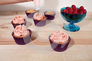 Frosting vanilla and raspberry cupcakes