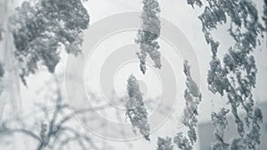 Frostwork. Decorative crystals of ice and snow on the window against the background of the city and sky. Frosty pattern. Ice