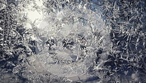 Frostwork on glass in winter. Light ice pattern. Snowflakes on frozen window. Frost on glass.