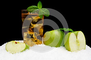 Frosty apple juice,ice cubes and apple with leaves on black on snow