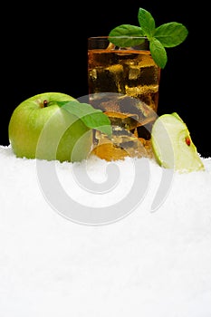 Frosty apple juice,ice cubes and apple with leaves on black on snow