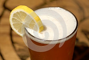 Frosty glass of beer with lemon slice