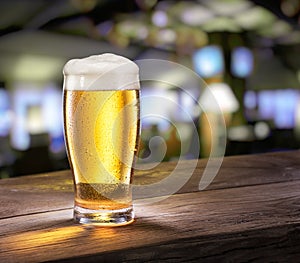 Frosty glass of light beer on the bar counter.