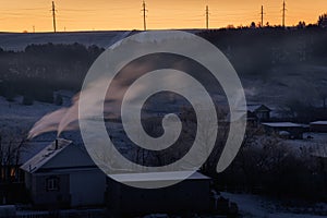 On a frosty morning, smoke from stoves billows from the houses