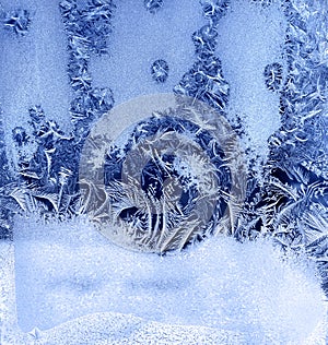 Frosty pattern on a winter window. Abstract blue winter background
