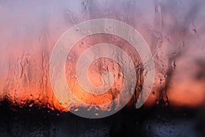 Frosty patterns on glass, sunset is in a window