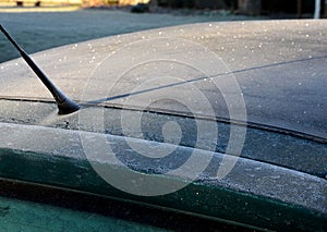 Frosty roof of a green passenger car with heavy icing. police may fine for poorly cleaned car. there must be no snow or ice in the