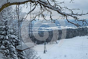 Frosty snow on old wooden swing near winter forest photo