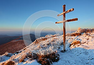 A frosty sunset in mountains with cross