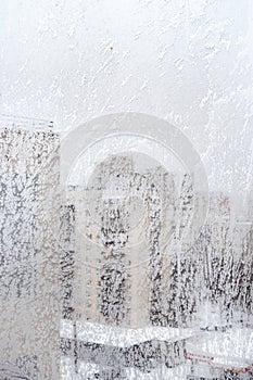 Frosty window glass and cityscape on winter day