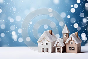 Frosty winter cute houses on snowfall background with copyspace. Festive blue background with Christmas lights, blurred background
