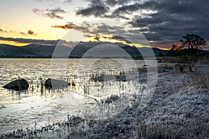 A frosty winter sunrise and fiery skies at Bassenthwaite Lake in the Lake District National Park, Cumbria, England