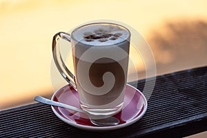 Frothed cappuccino with spoon on a railing