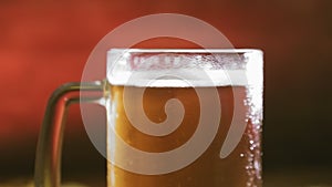 A frothing cold light beer in a glass mug rotates in a circle.